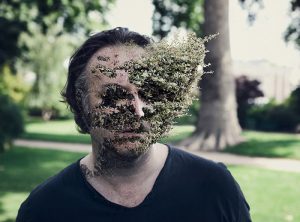 A man whose face appears to be turning into a plant
